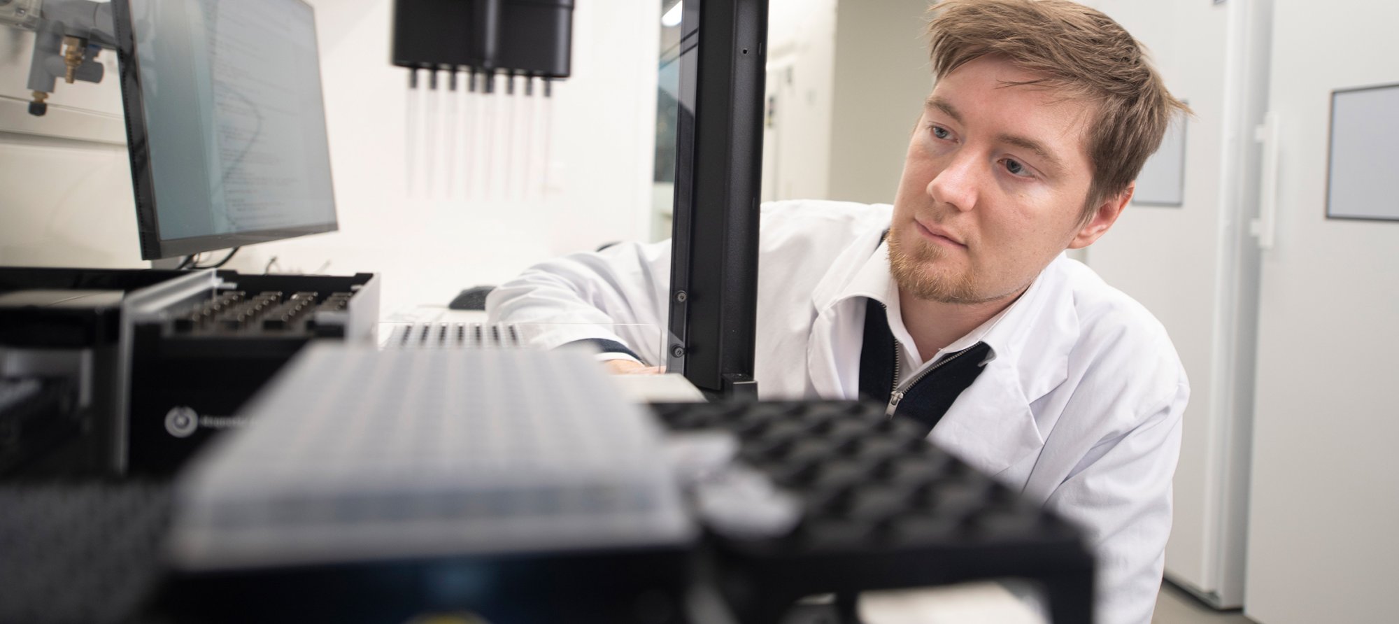 Oskari Vinko operating an OT-2 liquid handler as it performs automated sample preparation
